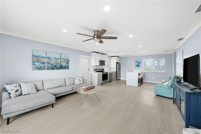 living room with light hardwood / wood-style floors, ornamental molding, and ceiling fan