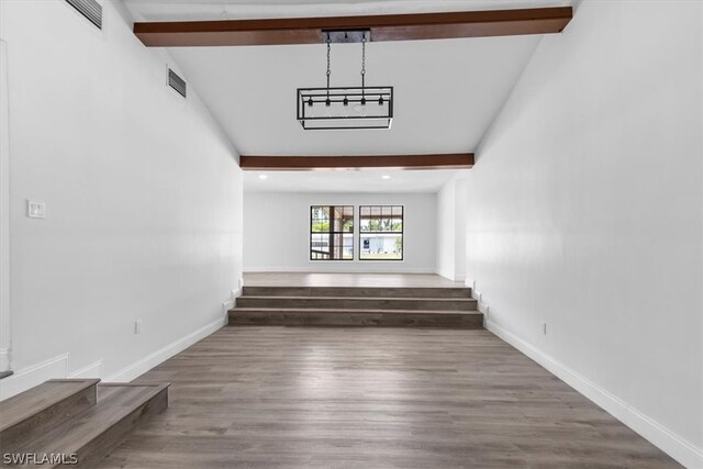 empty room featuring vaulted ceiling with beams and hardwood / wood-style floors