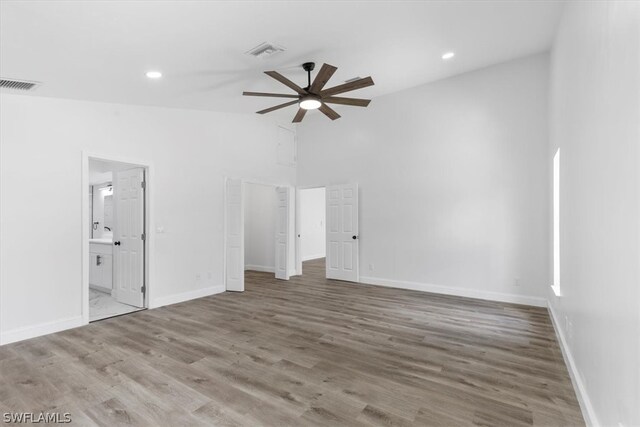 empty room with high vaulted ceiling, ceiling fan, and hardwood / wood-style floors