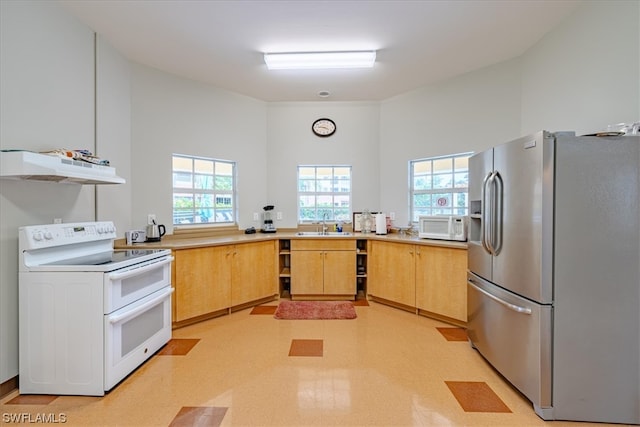 kitchen with light brown cabinetry, white appliances, a towering ceiling, and sink