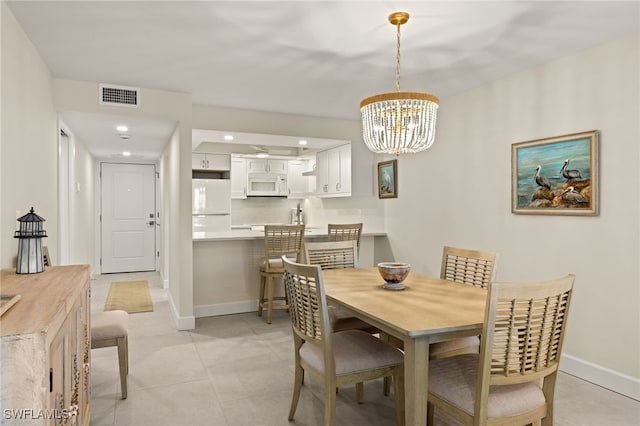 tiled dining room with an inviting chandelier