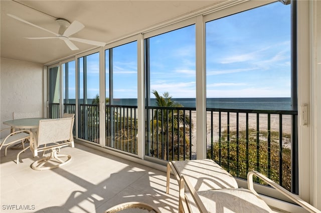 sunroom featuring a water view, a healthy amount of sunlight, and a view of the beach