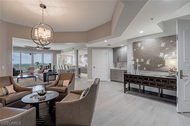 living room featuring ceiling fan with notable chandelier and light hardwood / wood-style flooring