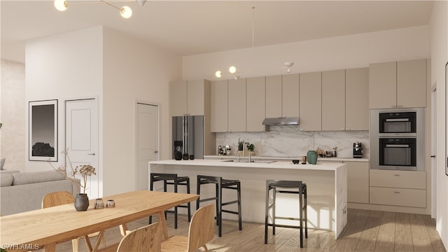 kitchen featuring a kitchen bar, light hardwood / wood-style floors, stainless steel refrigerator with ice dispenser, sink, and gray cabinetry