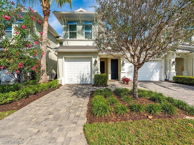 view of front of property with decorative driveway, an attached garage, and stucco siding