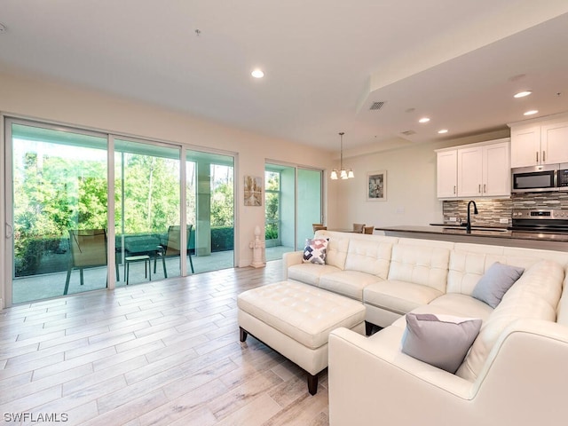 living room featuring light wood-type flooring, recessed lighting, and visible vents