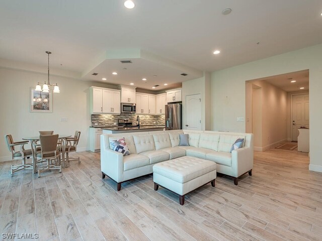 living room featuring sink, an inviting chandelier, and light hardwood / wood-style floors