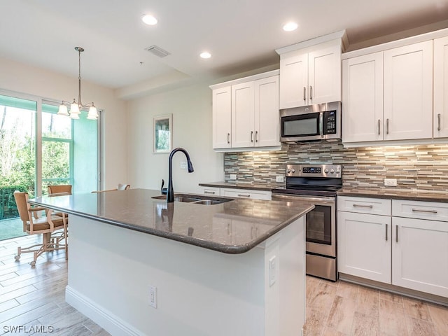 kitchen featuring a sink, visible vents, appliances with stainless steel finishes, light wood-type flooring, and decorative backsplash