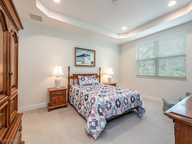 bedroom featuring a tray ceiling and light carpet