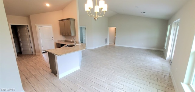 kitchen with hanging light fixtures, sink, an inviting chandelier, light stone counters, and lofted ceiling