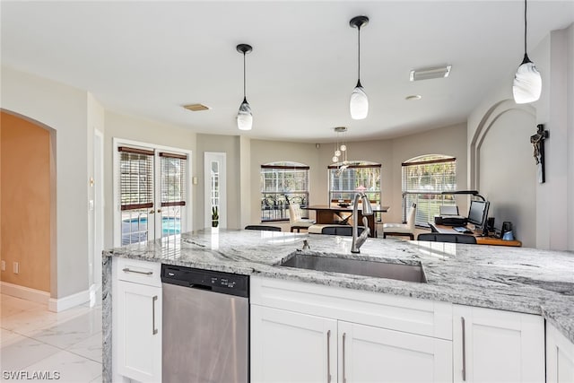 kitchen featuring light stone counters, white cabinets, stainless steel dishwasher, pendant lighting, and sink