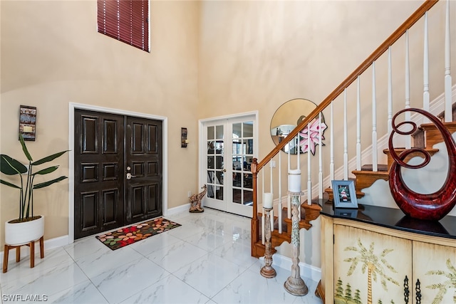 tiled foyer featuring french doors and a towering ceiling