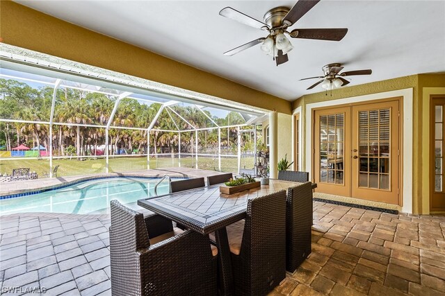 view of swimming pool with a patio area, ceiling fan, and glass enclosure