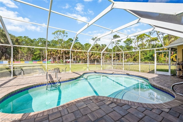 view of pool featuring glass enclosure, a yard, and a patio