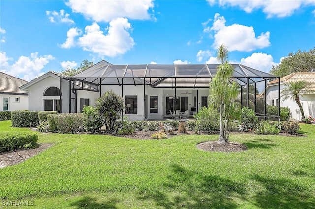 back of property with a lawn, ceiling fan, and a lanai