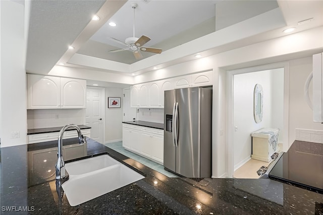 kitchen with decorative backsplash, stainless steel refrigerator with ice dispenser, a raised ceiling, sink, and white cabinets