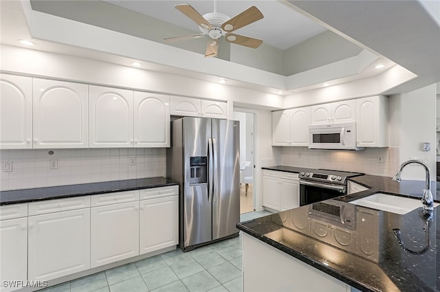 kitchen featuring ceiling fan, stainless steel appliances, light tile patterned floors, tasteful backsplash, and white cabinets