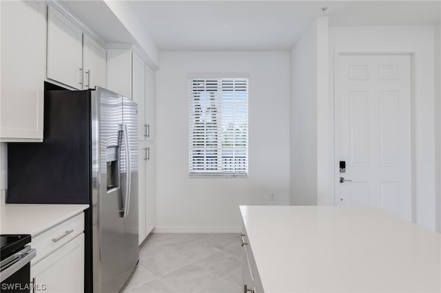 kitchen with white cabinets, light tile floors, and stainless steel range with electric stovetop