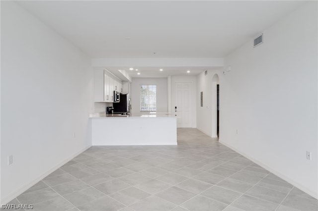 kitchen with white cabinets, light tile flooring, kitchen peninsula, and fridge