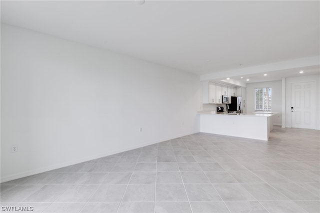 unfurnished living room featuring light tile floors and sink