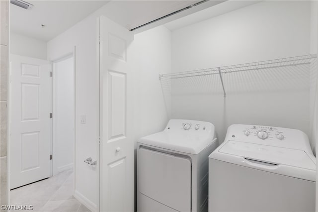 clothes washing area with independent washer and dryer and light tile floors