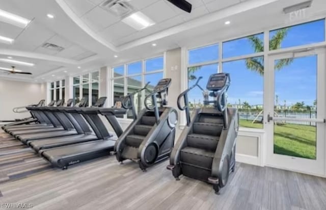 gym with light hardwood / wood-style floors, ceiling fan, and a wealth of natural light