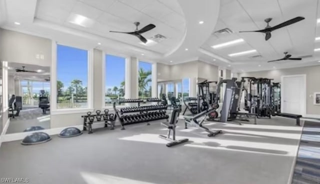 gym with a raised ceiling, visible vents, baseboards, and ceiling fan