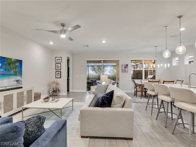 living room featuring light hardwood / wood-style floors and ceiling fan with notable chandelier