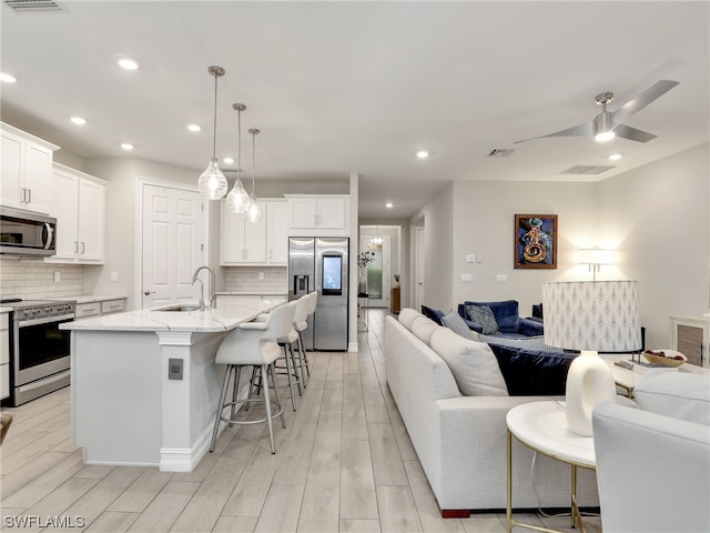 kitchen featuring a kitchen bar, stainless steel appliances, a kitchen island with sink, and tasteful backsplash