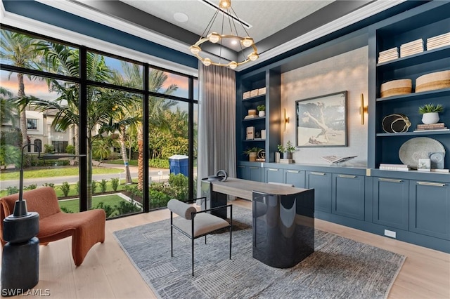 office area featuring a tray ceiling, an inviting chandelier, ornamental molding, and light wood-type flooring