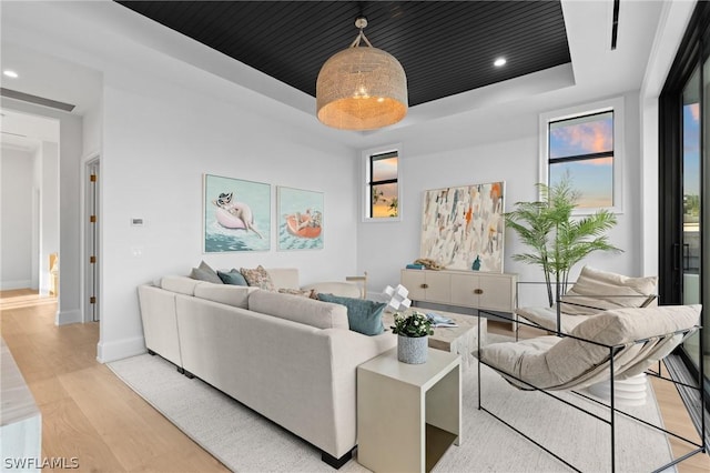 living room featuring a raised ceiling and light wood-type flooring