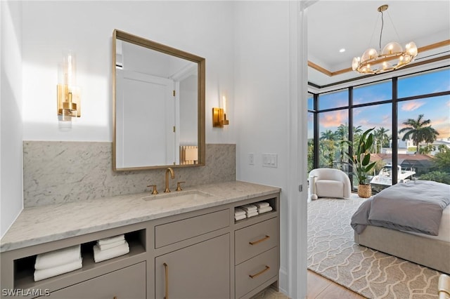 bathroom featuring vanity, ornamental molding, tasteful backsplash, wood-type flooring, and a chandelier