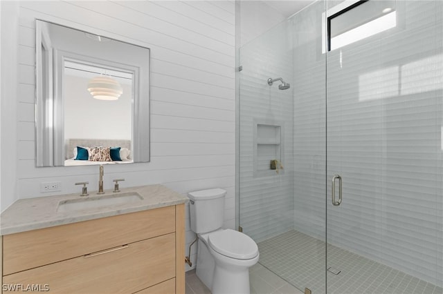 bathroom with vanity, a shower with door, tile patterned flooring, toilet, and wood walls