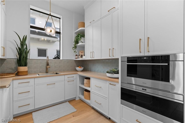 kitchen featuring light hardwood / wood-style flooring, decorative light fixtures, white cabinetry, and sink