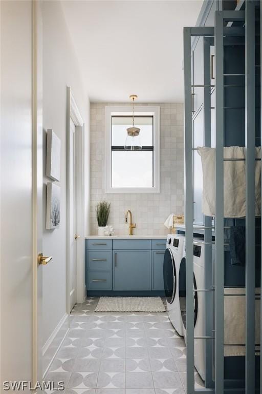 laundry room with light tile patterned floors, sink, and washing machine and clothes dryer