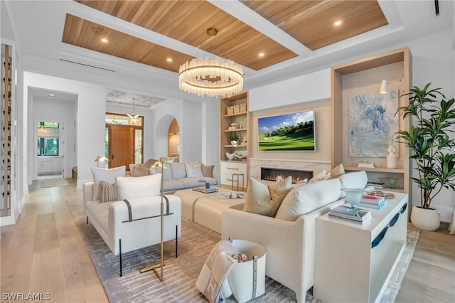 living room with wood ceiling, light hardwood / wood-style flooring, built in features, a premium fireplace, and a chandelier