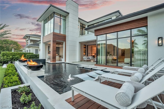 back house at dusk with an outdoor fire pit