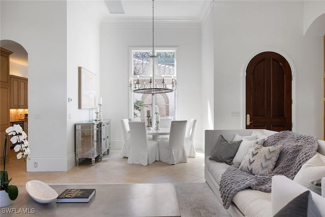 living room featuring a high ceiling, light tile patterned floors, an inviting chandelier, and crown molding