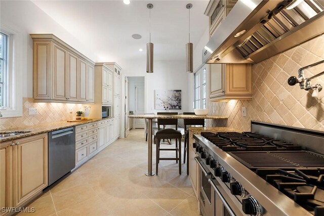 kitchen with light stone countertops, appliances with stainless steel finishes, backsplash, wall chimney exhaust hood, and pendant lighting