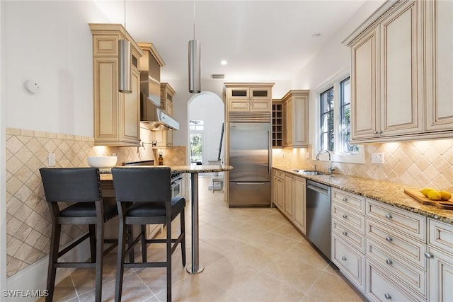 kitchen featuring appliances with stainless steel finishes, light stone counters, a wealth of natural light, sink, and hanging light fixtures