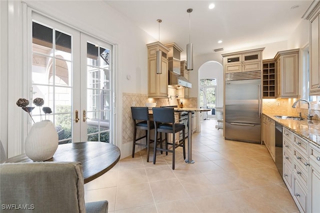 kitchen with light stone counters, sink, decorative light fixtures, and premium appliances