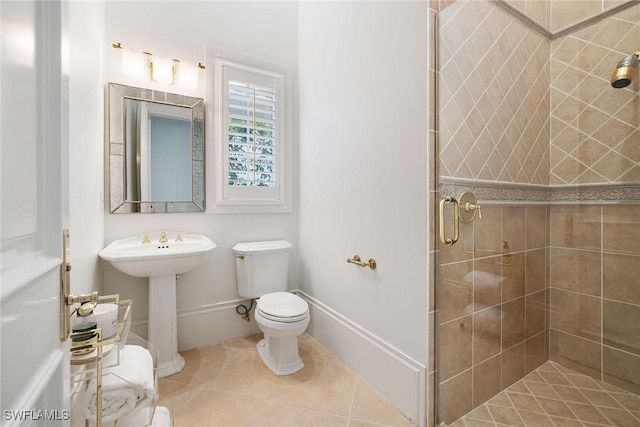 bathroom featuring tile patterned flooring, toilet, a shower with shower door, and sink