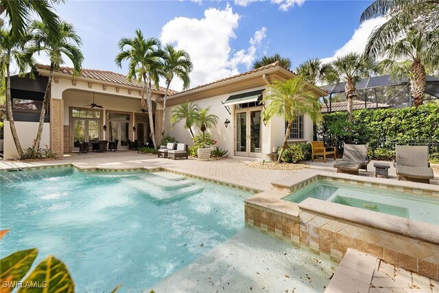 rear view of property with glass enclosure, ceiling fan, french doors, a pool with hot tub, and a patio