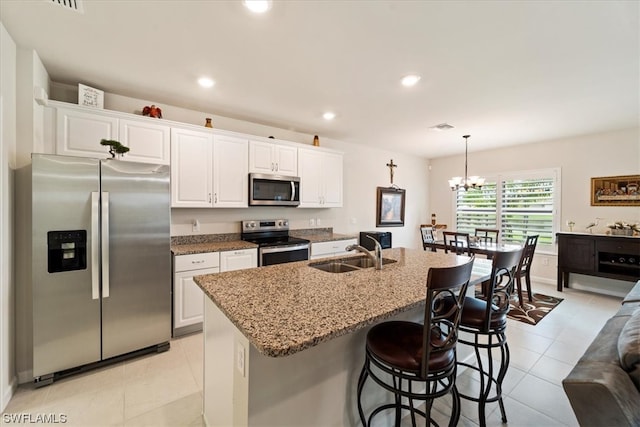 kitchen featuring light tile flooring, sink, stainless steel appliances, white cabinets, and a chandelier