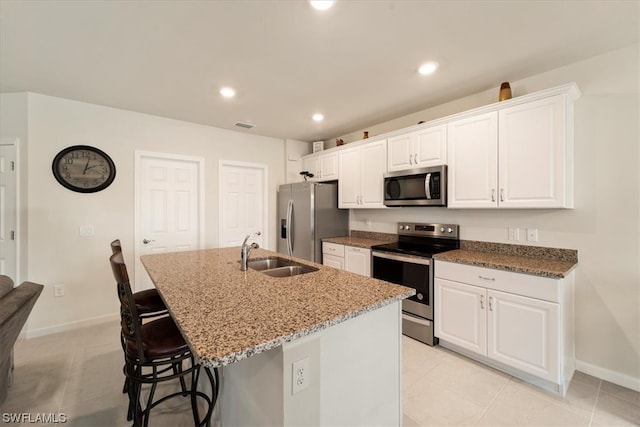 kitchen with appliances with stainless steel finishes, sink, an island with sink, light tile floors, and white cabinets