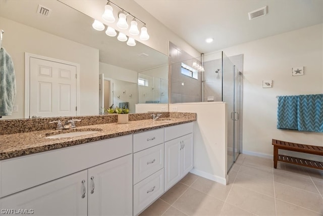 bathroom with tile flooring, vanity with extensive cabinet space, dual sinks, and an enclosed shower