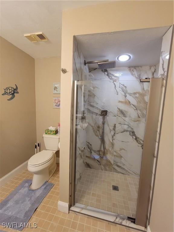 bathroom featuring tile patterned floors, toilet, and a shower with shower door