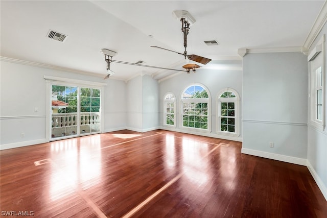 unfurnished room featuring a wealth of natural light, vaulted ceiling, crown molding, and hardwood / wood-style flooring