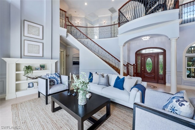 tiled living room featuring crown molding, a towering ceiling, and decorative columns