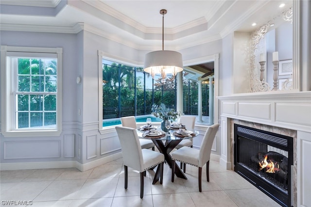 dining area featuring a wealth of natural light, light tile floors, a raised ceiling, and a chandelier